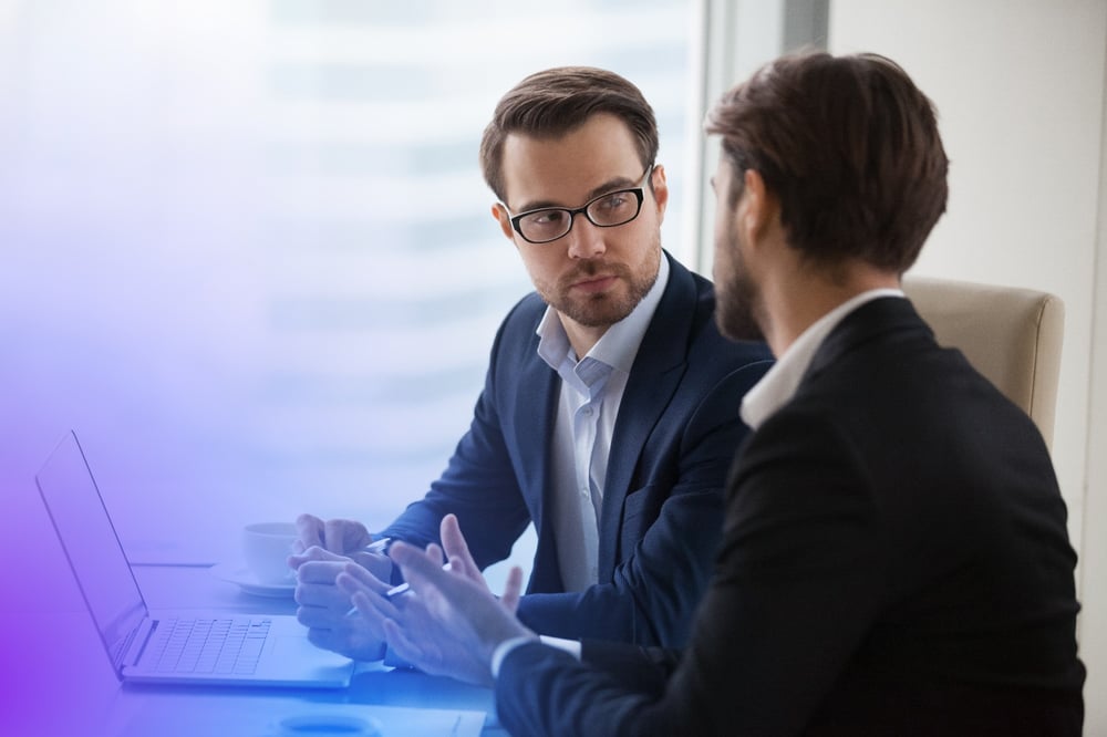 two men in discussion in front of a laptop 